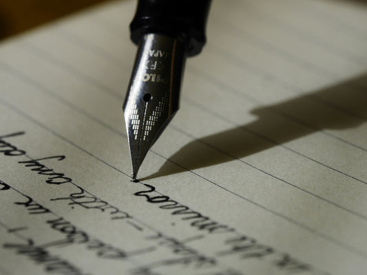 A fountain pen writing a handwritten letter in cursive on lined paper