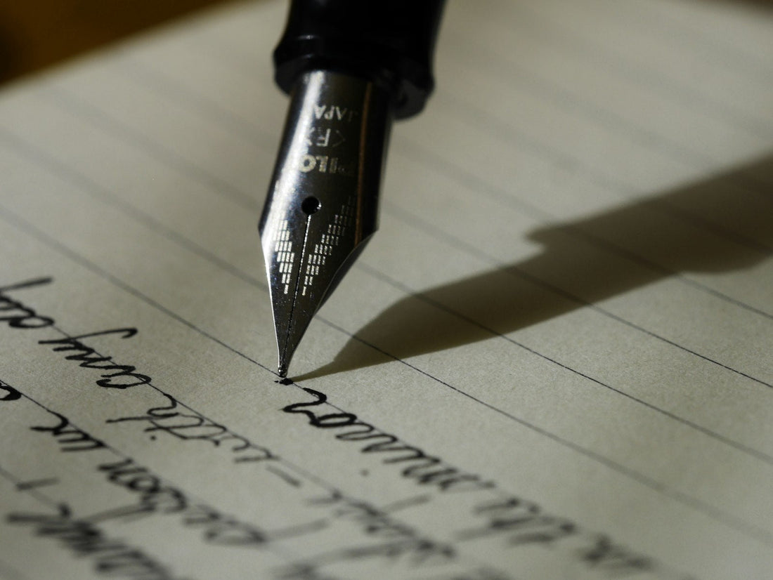 A child's hand writing a letter in pen on paper, a calm screen-free moment of handwriting practice