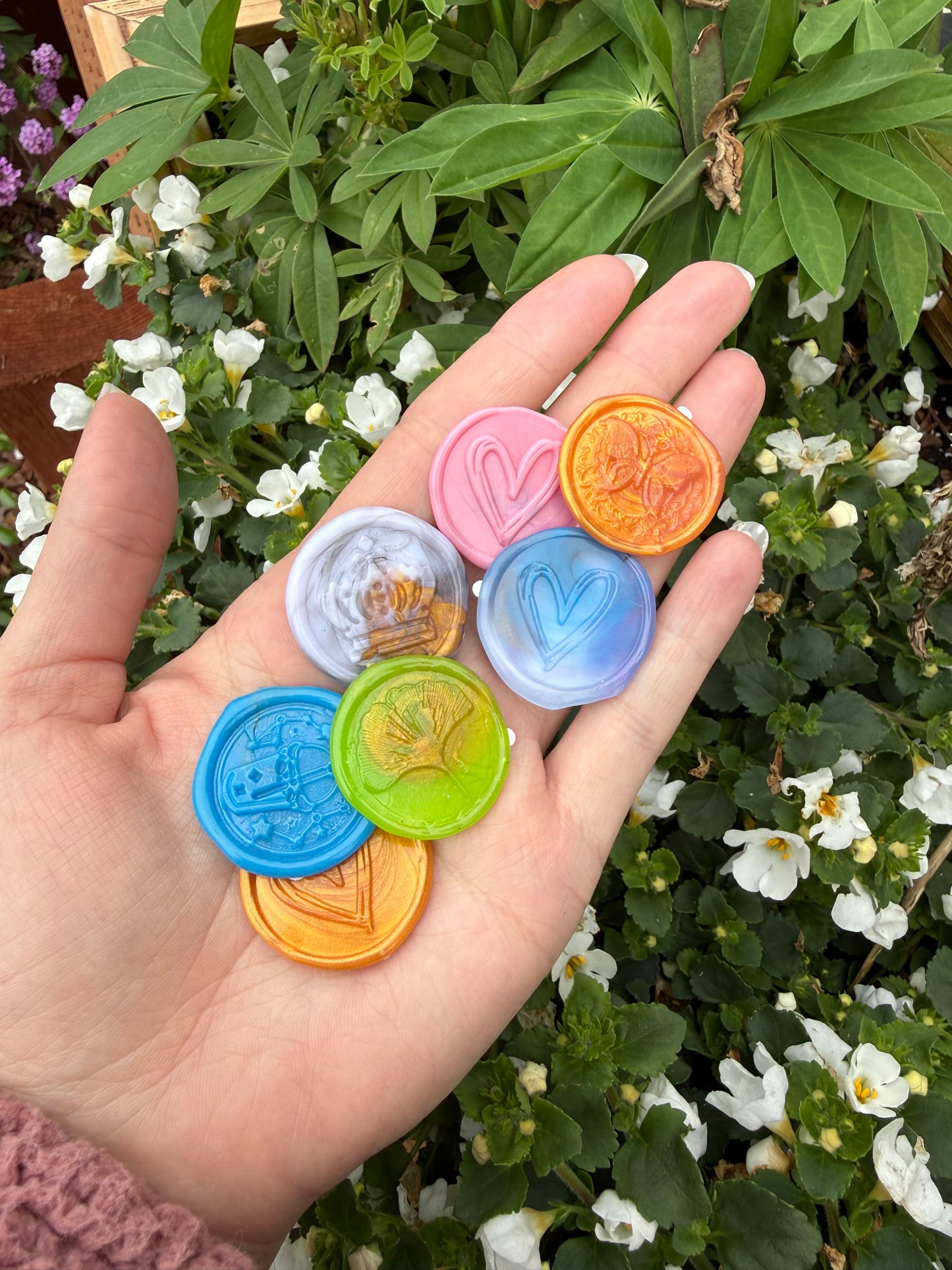 Hand holding a mix of handmade pearlescent wax seal stickers in a garden - Wax Seal Surprise Pack add-on for letter writing and snail mail kits